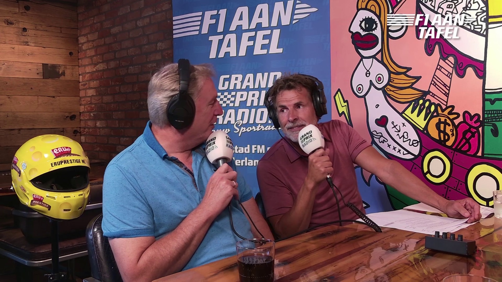 Twee tafelgasten met koptelefoon en microfoon tijdens een opname van F1 aan Tafel
