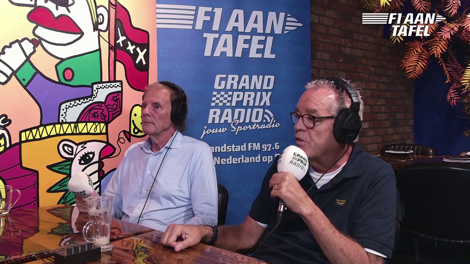 Twee gasten met koptelefoon in gesprek tijdens de opname van F1 aan Tafel